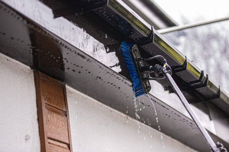 Professional window cleaning tool with water spray on exterior of building.